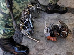Un soldado junto a armas recolectadas en el programa de despistolización. AP  /
