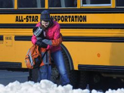Una madre abraza a su hijo antes de que aborde el autobús que lo llevará al colegio. AP  /