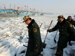 Policías examinan las condiciones del hielo en el Muelle Pesquero Xidayang, en Qingdao, provincia de Shandong. XINHUA /