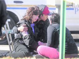 Drama. Dos residentes de Aurora consuelan a una persona impactada por el nuevo hecho de violencia. EFE /