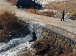 Un niño camina sobre un puente, bajo el cual no fluye agua, pero muestra restos de anilina. XINHUA /