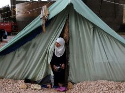 Una mujer siria asoma de su tienda en un campo de refugiados, en Líbano. AP /
