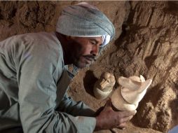 Un experto sostiene uno de los doce canopos encontrados en la tumba. EFE /