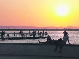 Malecón. Contempla el atardecer desde el muelle. Llega a él en una bicicleta rentada.  /