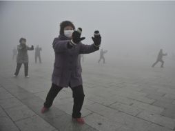 Un grupo de personas practica Taichi a pesar de la contaminación. AP /