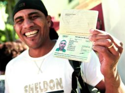 TROFEO EN MANO. Un cubano muestra feliz su pasaporte al salir de la Oficina de Inmigración y Extranjería en La Habana. EFE /