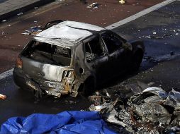 Un coche quemado y restos del helicóptero, en el lugar del accidente. EFE /