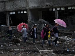 Una de la serie de fotos de Armangué, donde se ve una niñas atravesando unas ruinas para ir a la escuela. AP /