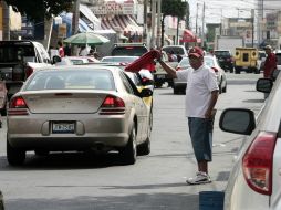 El muchacho se encarga de cinco espacios para estacionar, en una calle oscura e insegura. ARCHIVO /