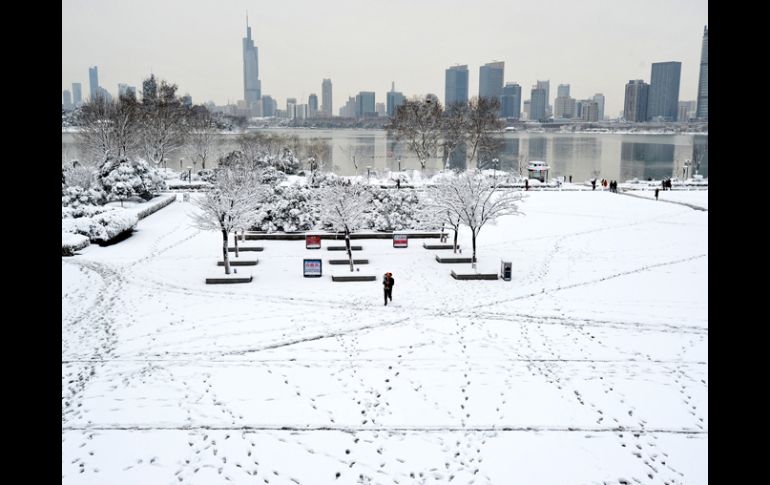 Un hombre carga a un niño en un parque cubierto de nieve hoy, en Nanjing, China. AP /