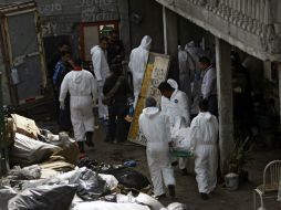 Personal forense retira los cuerpos del lugar mientras la policía Ministerial y el ejército hacen investigaciones. AFP /