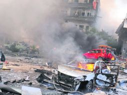 DÍA DE HORROR. Personas corren cerca del sitio donde estalló un coche-bomba en un barrio popular de la capital siria. AFP /