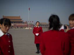 Edecanes toman fotografías en la plaza Tiananmen, donde se puede ver la contaminación existente. AFP /