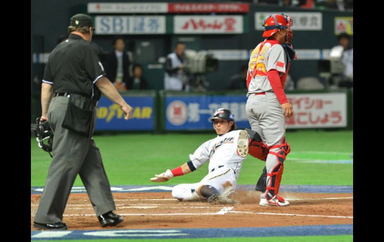 Yoshio Itoi, de Japón, se barre en el home ante el catcher Wang Wei de China. AFP /
