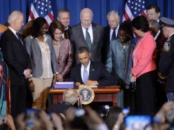 El mandatario estadounidense firma rodeado de personas. EFE /