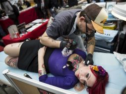 Un hombre realiza un tatuaje a una chica durante la Feria Internacional del Tatuaje en París. EFE /
