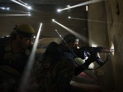 Dos milicianos de la oposición al régimen sirio que montan guardia dentro de un edificio. AFP /