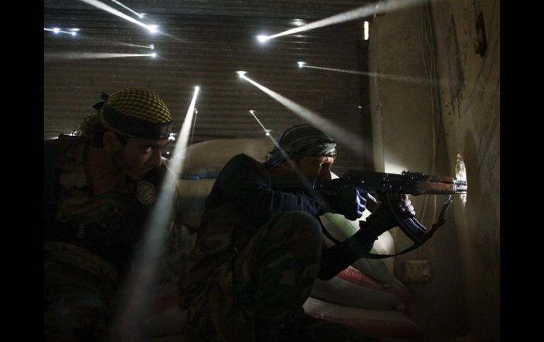 Dos milicianos de la oposición al régimen sirio que montan guardia dentro de un edificio. AFP /