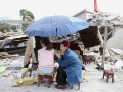 Unas mujeres descansan junto a las ruinas de su casa que fue derrumbada por el sismo. AFP /