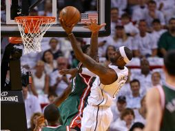 James salta para anotar, mientras otros jugadore tratan de que no lo logre. AFP /