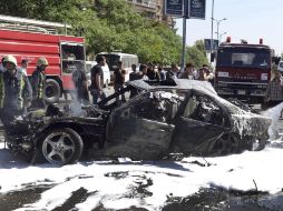 Miembros de los servicios de emergencia trabajan junto un vehículo dañado por el atentado contra el convoy del primer ministro sirio. EFE /