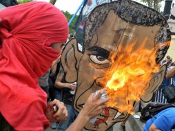 Miembros de ‘’Los Anarcos’’ corean consignas antiestadounidenses y queman una imagen de Obama. AFP /