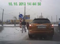 Captura de pantalla del video, la cual muestra a un hombre que se baja de su auto para ayudar a una anciana a cruzar la calle. ESPECIAL /