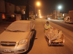 Un vendedor ambulante pasa junto a un coche cubierto de una capa de ceniza del volcán Popocatépetl en Puebla. AFP /