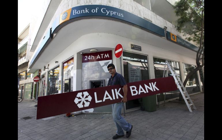 Un hombre cubre la serigrafía del banco Laiki por la del Banco de Chipre. EFE /