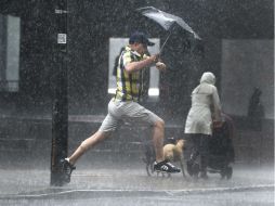 Un hombre brinca una acumulación de agua generada por fuertes lluvias. AP /