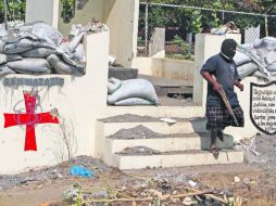 Policía comunitario al lado de una pinta en referencia a Nazario Moreno González, fallecido líder de los Caballeros Templarios. AP /