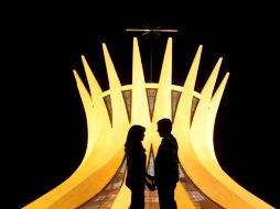 La silueta de una pareja se recorta frente a la catedral de Brasilia, diseño del arquitecto Niemeyer. ARCHIVO /