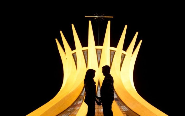 La silueta de una pareja se recorta frente a la catedral de Brasilia, diseño del arquitecto Niemeyer. ARCHIVO /