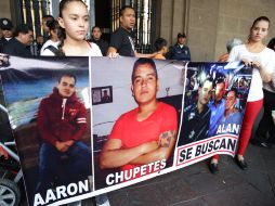 Familiares de los desaparecidos muestran una manta con sus fotografías. ARCHIVO /