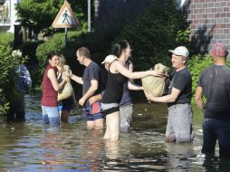 Voluntarios hacen una cadena humana para transportar sacos de tierra en una calle inundada de Magdeburgo, Alemania. EFE /
