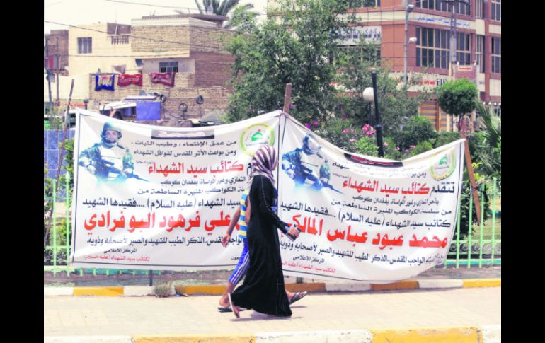 Personas pasan delante de carteles alusivos a Mahmud Abbas, activista chií iraquí asesinado en Siria. AP /