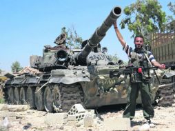 Un rebelde posa frente a un tanque confiscado en un cuartel a las fuerzas del régimen de Bashar al Assad, en la ciudad de Sermin. AFP /