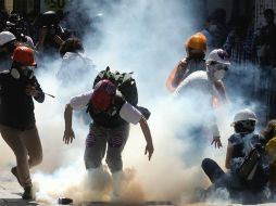 Los manifestantes corren en medio de gas lacrimógeno lanzado por la policía durante los enfrentamientos. EFE /