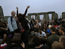 Varios de los asistentes levantan las manos para recibir el verano boreal en Stonehenge. AP /