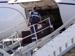 Trabajadores en el aeropuerto colocando en el avión un féretro identificado como el de Gandolfini. EFE /