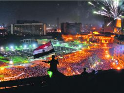Un hombre agita la bandera egipcia en una azotea, desde donde se ve a la multitud que se congregó para protestar en la plaza Tahrir. AFP /