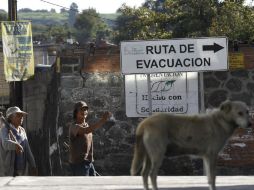 Dos personas caminan frente a una señal de evacuación este, en Santiago Xalitzintla, localizado a las faldas del Popocatépetl. EFE /