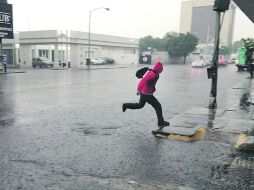 Avenida 16 de Septiembre. Un peatón corre para librar un charco durante la lluvia de ayer. EL INFORMADOR /