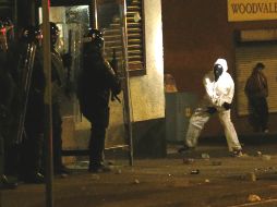 Un manifestante ataca a la barrera de los policías antimotines de Belfast. AP /