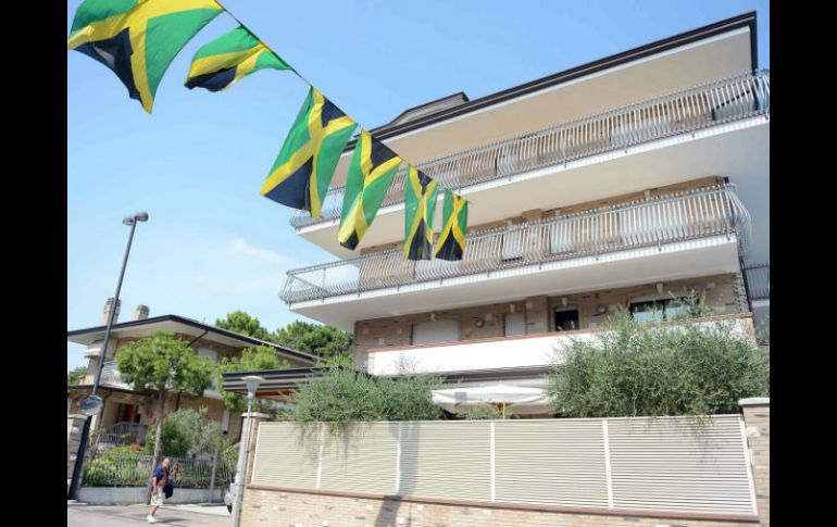 Banderas de Jamaica cuelgan de un balcón del hotel Fra I Pini, donde los atletas jamaicanos se encuentran alojados. AP /
