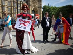 Un miembro de la comunidad homosexual es visto afuera del parlamento inglés con un letrero que agradece la aprobación de la ley. AFP /