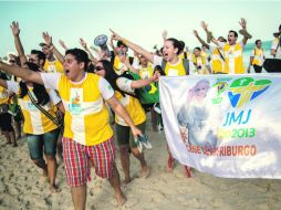 En la víspera de la llegada del Papa, algunos jóvenes peregrinos caminan por la playa de Ipanema en Río de Janeiro. AFP /