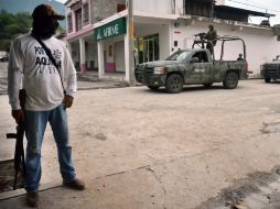 En la imagen, militares recorren el municipio de Aquila, ante la presencia de un elemento comunitario de autodefensa. AP /