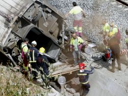 Los bomberos y el personal de Renfe trabajan  retirando los restos de un vagón. EFE /
