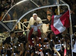 El Papa Francisco carga a un niño en medio de miles de simpatizantes en Copacabana. EFE /
